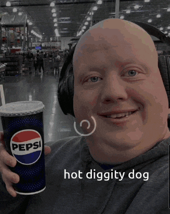 a bald man wearing headphones holds a pepsi cup