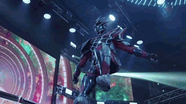a man in a red and black suit is standing in front of a stage