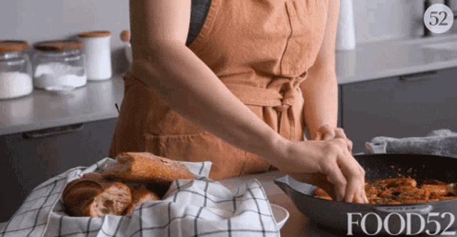 a woman in an apron is preparing food in a pan with the number 52 on the bottom