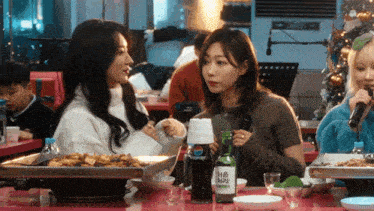 a bottle of pepsi sits on a table next to two women