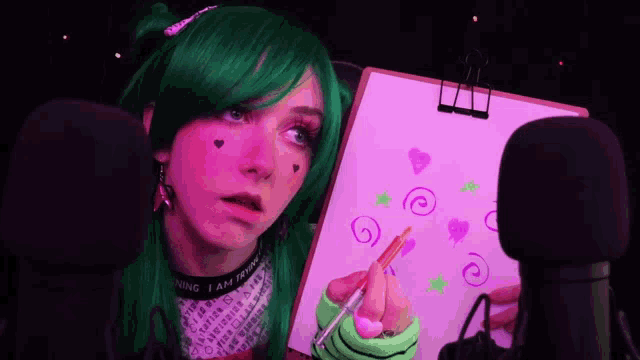 a woman with green hair is drawing on a clipboard with a brush