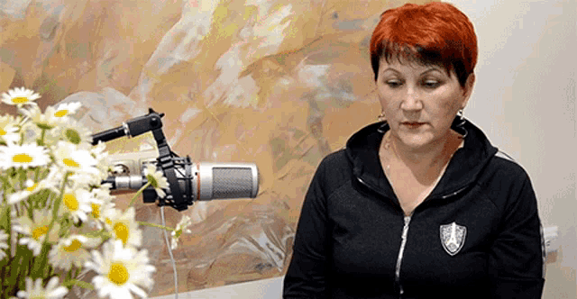 a woman sitting in front of a microphone with a shield on her jacket