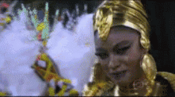 a woman in a gold costume is smiling in a blurry photo