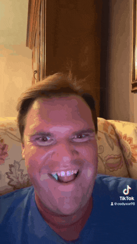 a man sitting on a couch with his mouth open and a tik tok sticker on the bottom