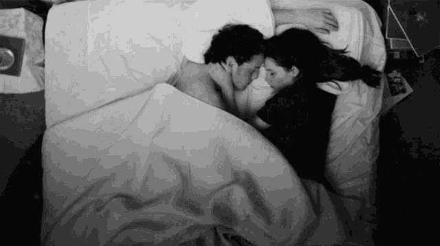 a black and white photo of a man and woman sleeping together