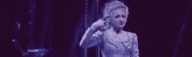 a woman in a purple dress is standing in front of a purple curtain .