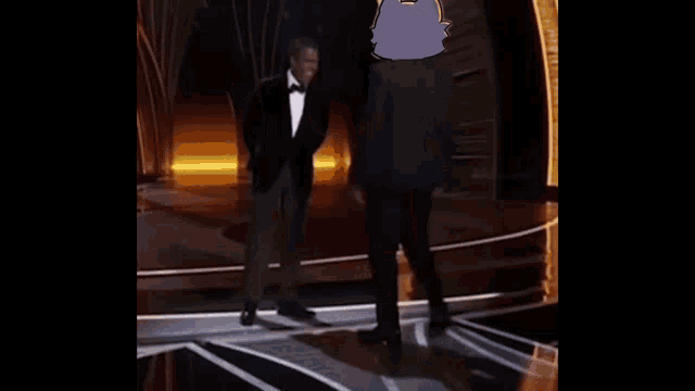 a man in a tuxedo is walking on a stage with a cartoon cat .