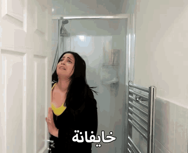 a woman is standing in a bathroom with arabic writing on the door