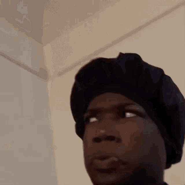 a close up of a person wearing a black hat and making a funny face .