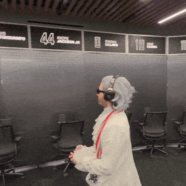 a man wearing headphones is standing in front of a wall with the number 44 on it