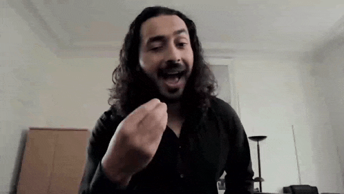 a man with long hair and a beard is making a funny face while talking on a video call .
