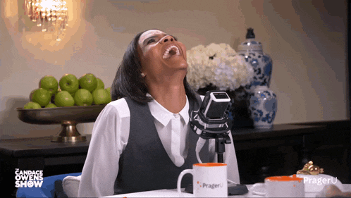 a woman is laughing in front of a prager u mug