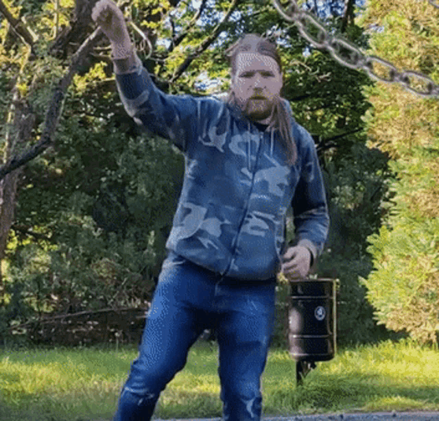 a man with long hair and a beard is holding a black barrel
