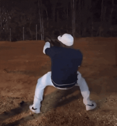 a man in a blue shirt and white pants is standing on his knees holding a baseball bat
