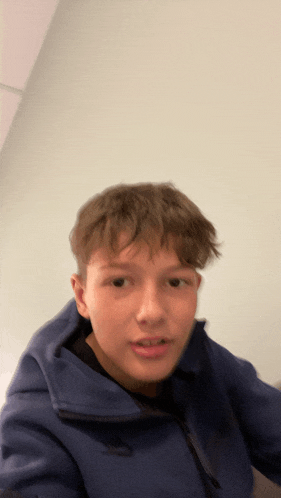 a young boy wearing a blue nike hoodie looks at the camera