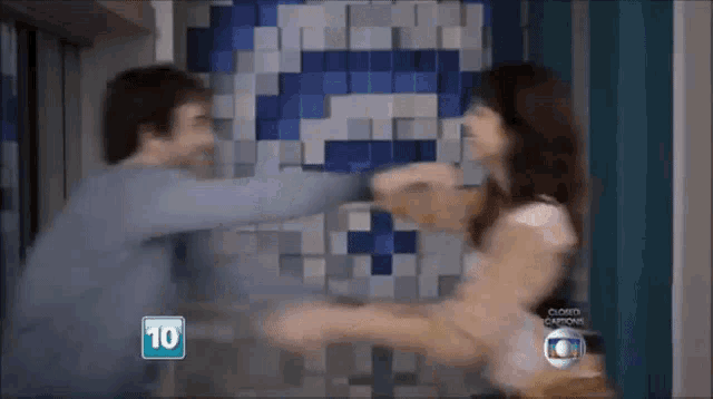 a man and a woman are fighting in front of a tiled wall with the number 10 on it