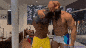 two shirtless men are standing next to each other in a living room with the words watchfighters on the bottom right
