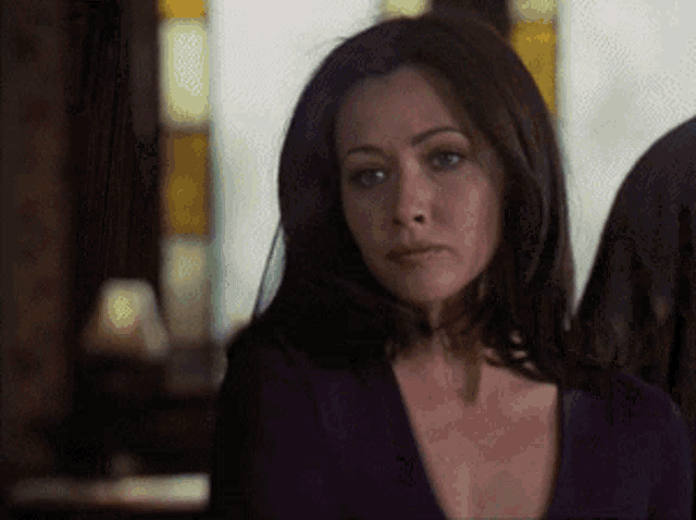 a woman in a purple sweater looks at the camera