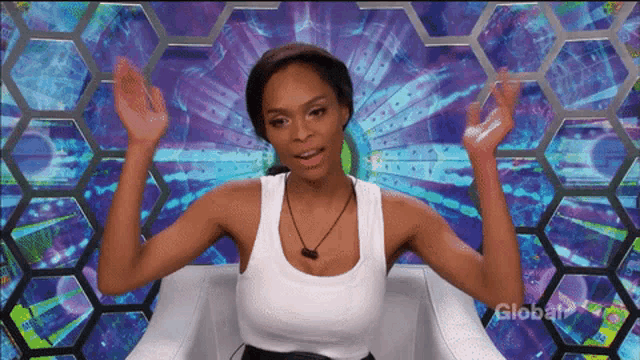 a woman in a white tank top is sitting in front of a screen that says global on it
