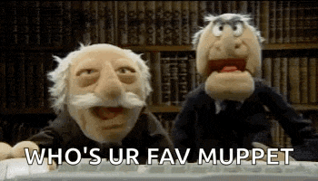 two muppets are sitting next to each other in front of a computer keyboard in a library .