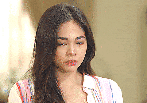 a woman with a tear running down her face is wearing a striped shirt
