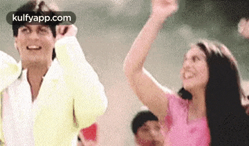 a man and a woman are standing next to each other waving their hands in the air .