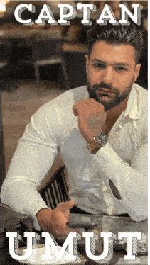 a man in a white shirt is sitting at a table with the name kaptan umut written on the bottom