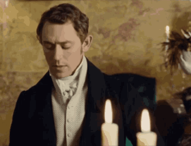 a man in a suit stands in front of a candle