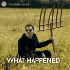 a man is sitting in a field holding a pitchfork and the words what happened are above him .