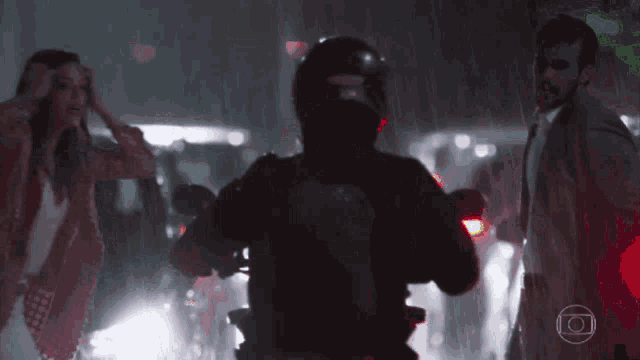 a man wearing a helmet is riding a motorcycle in the rain at night