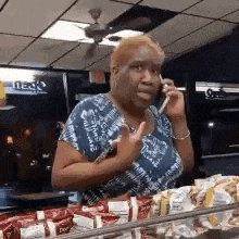 a woman is talking on a cell phone in front of a display case of food .