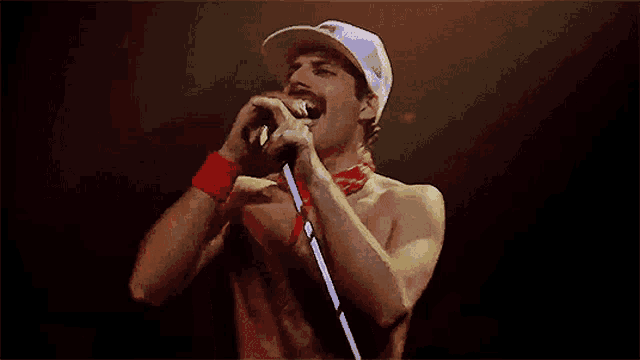 a man without a shirt singing into a microphone with a hat that says ' a ' on it