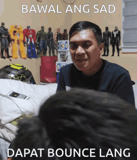 a man sitting in front of a wall of action figures with the caption bawal ang sad