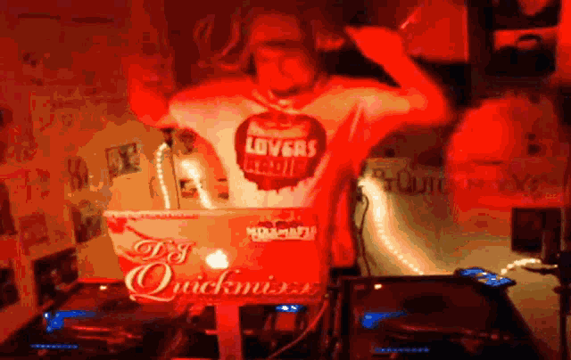 a man wearing a shirt that says lovers is playing music on a laptop