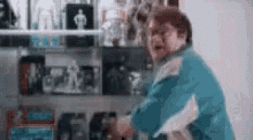 a man in a blue jacket is standing in front of a shelf with a lot of toys on it .