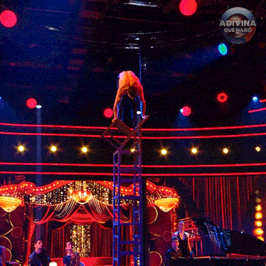 a man stands on a ladder on a stage with a sign that says adivina que hago