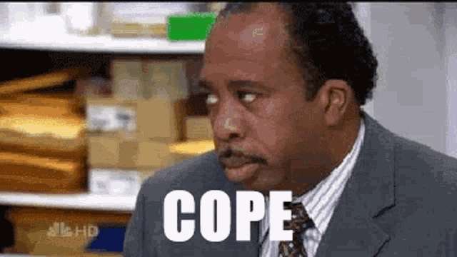 a man in a suit and tie is making a funny face with the word cope written on his face .