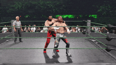 two wrestlers are fighting in a ring with a referee