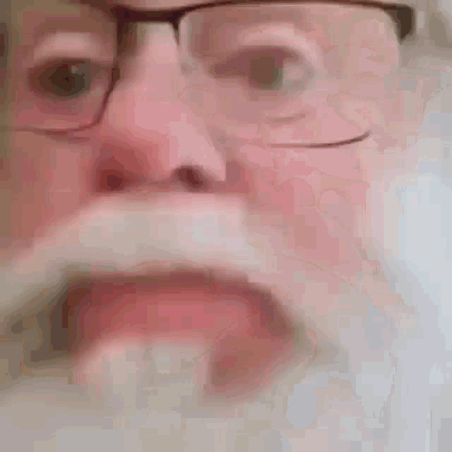 a close up of a man with glasses and a beard .