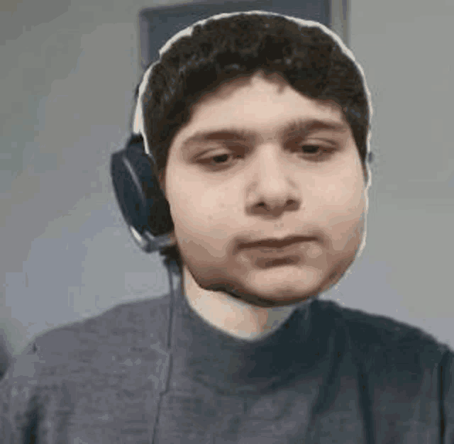 a young man wearing headphones is looking at the camera and making a funny face .