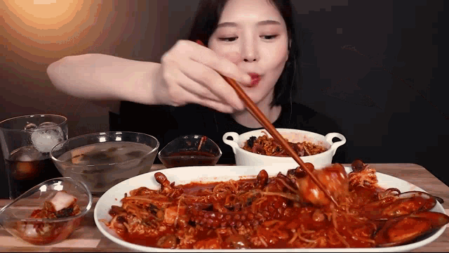 a woman is eating a plate of food with chopsticks and a spoon