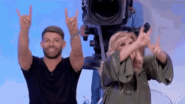 a man and a woman are making a devil horns sign with their hands .