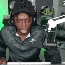 a man wearing headphones and a hat is sitting in front of a microphone with the number 2 on the bottom