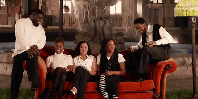 a group of people are sitting on a couch in front of a fountain