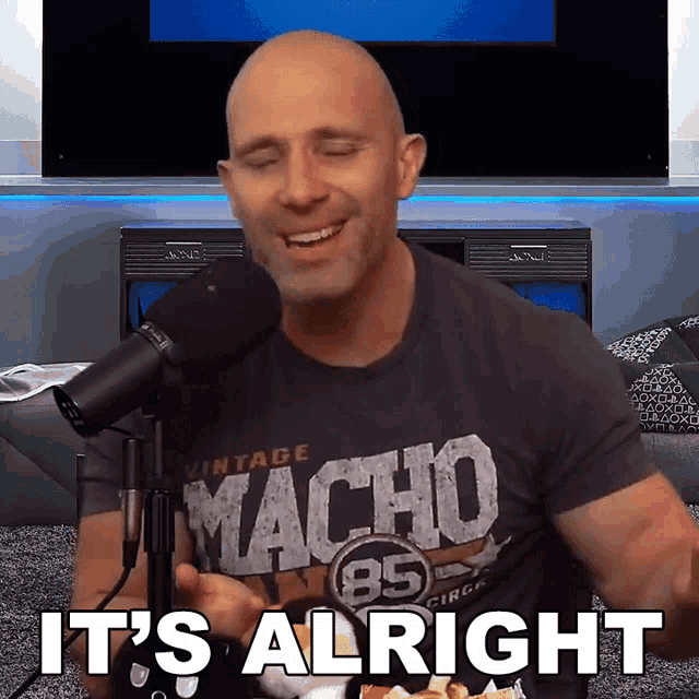 a man wearing a vintage macho shirt says it 's alright in front of a microphone
