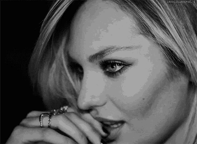 a close up of a woman 's face with a ring on her finger .