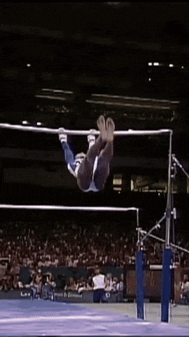 a gymnast is doing a trick on a bar while a crowd watches