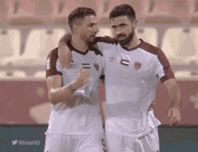 two soccer players hugging each other on a field