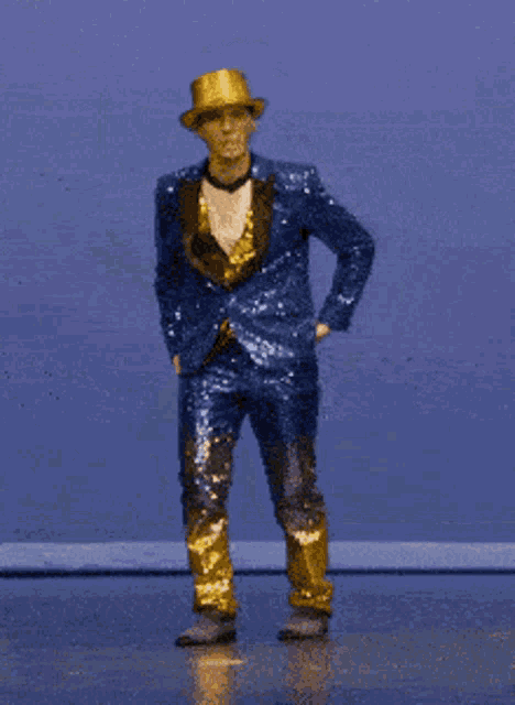 a man in a blue sequined suit and gold hat is dancing