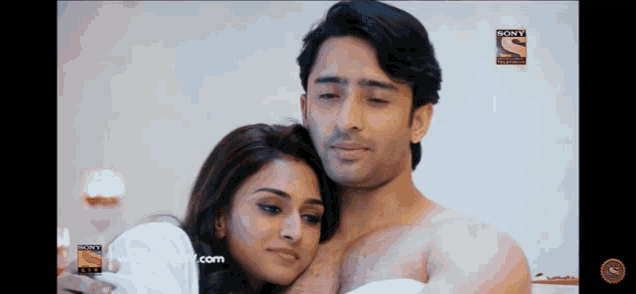 a man without a shirt is hugging a woman with a sony tv logo in the background